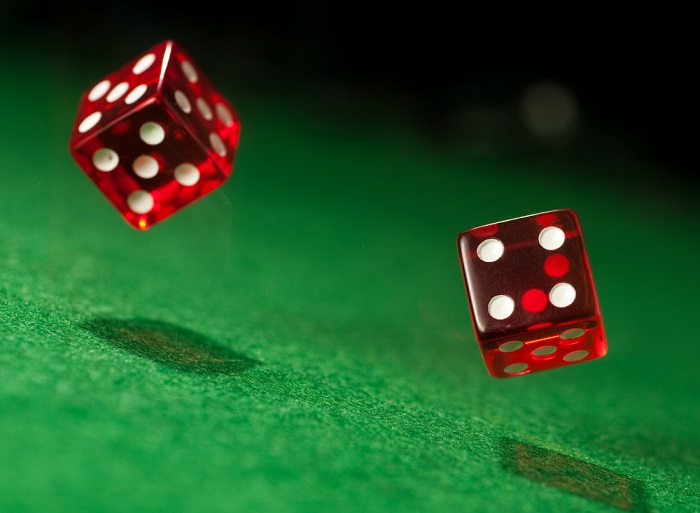 Two red dice caught in mid-air above green cloth surface